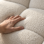 A hand pressing into the looped bouclé of the Cloud Corner Sectional in Cloud White, between two tufted squares